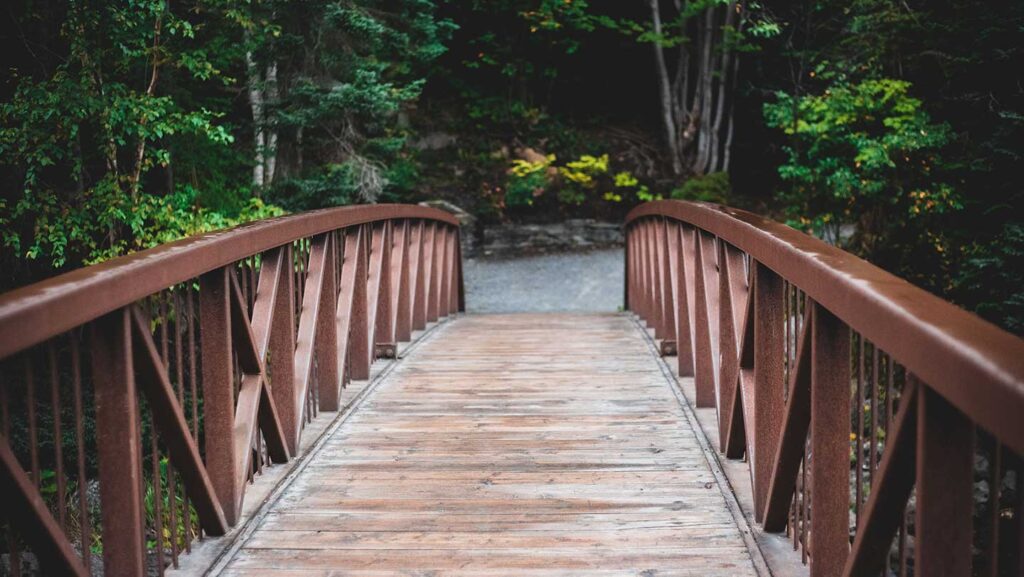 pov walking over wood slat bridge